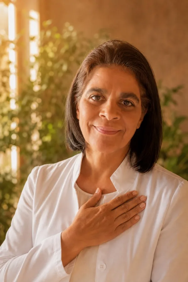 Maria de Fátima em retrato caloroso, a mão no peito